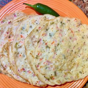 onion uthappam with onions, green chili, bell peppers, tomato and cliantro